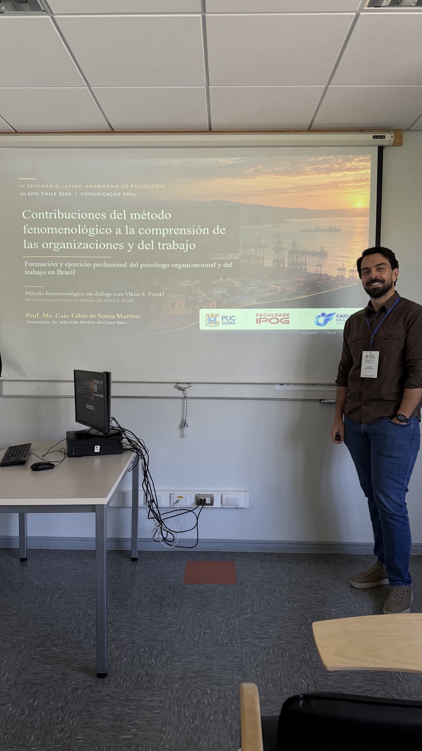 Caio Fábio Martins ao lado da apresentação de seu trabalho no ULAPSI Chile 2026